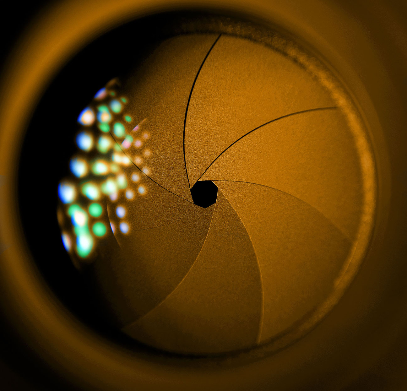 Close-up of a camera lens aperture blades catching warm golden light, an evocative image of filmmaking craft